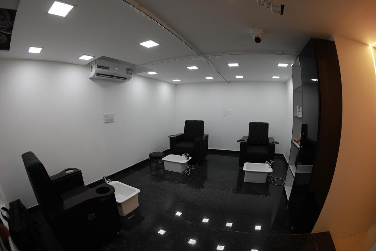 Pedicure lounge with three black spa chairs on a polished dark granite floor
