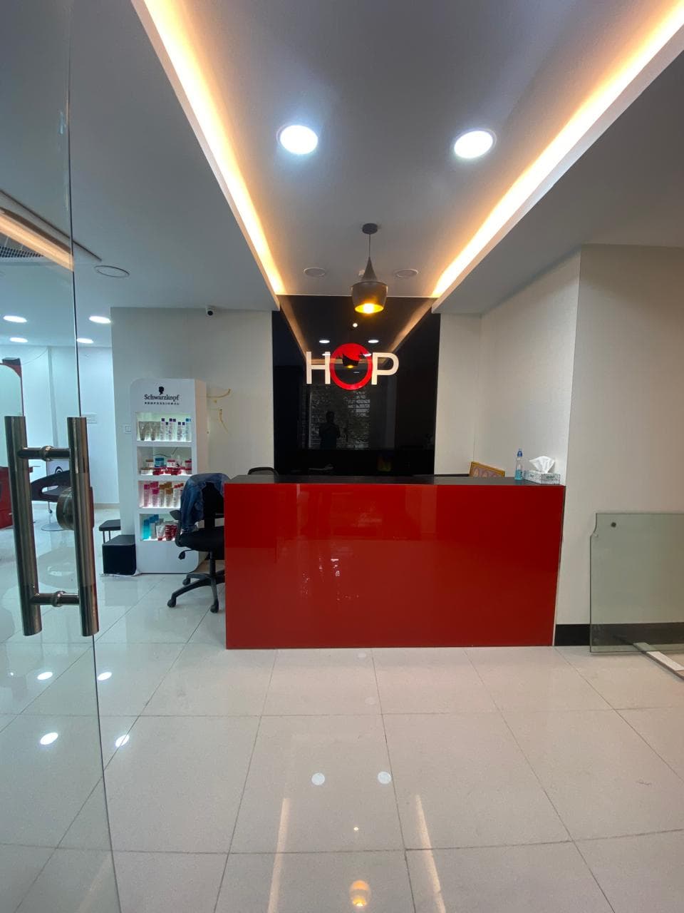 HOP Salon reception with a red desk and the backlit HOP logo behind it
