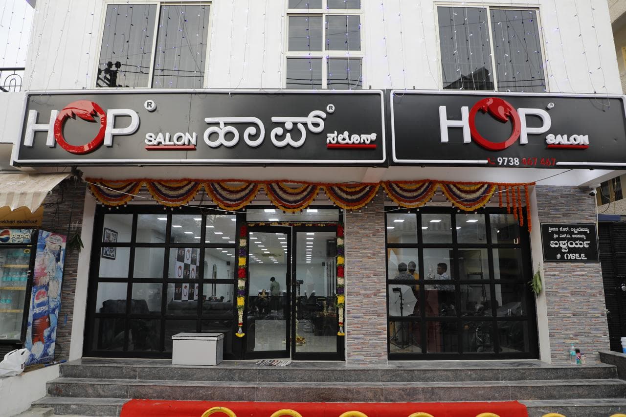 HOP Salon storefront with illuminated English and Kannada signage, dressed with marigold garlands